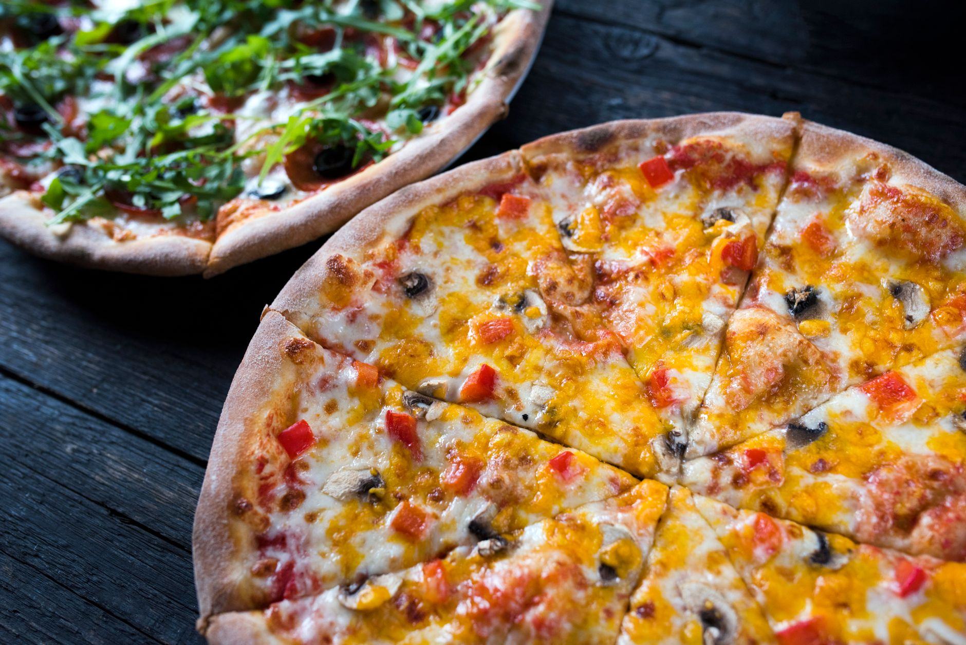 Nybakade pizzor på mörkt träbord